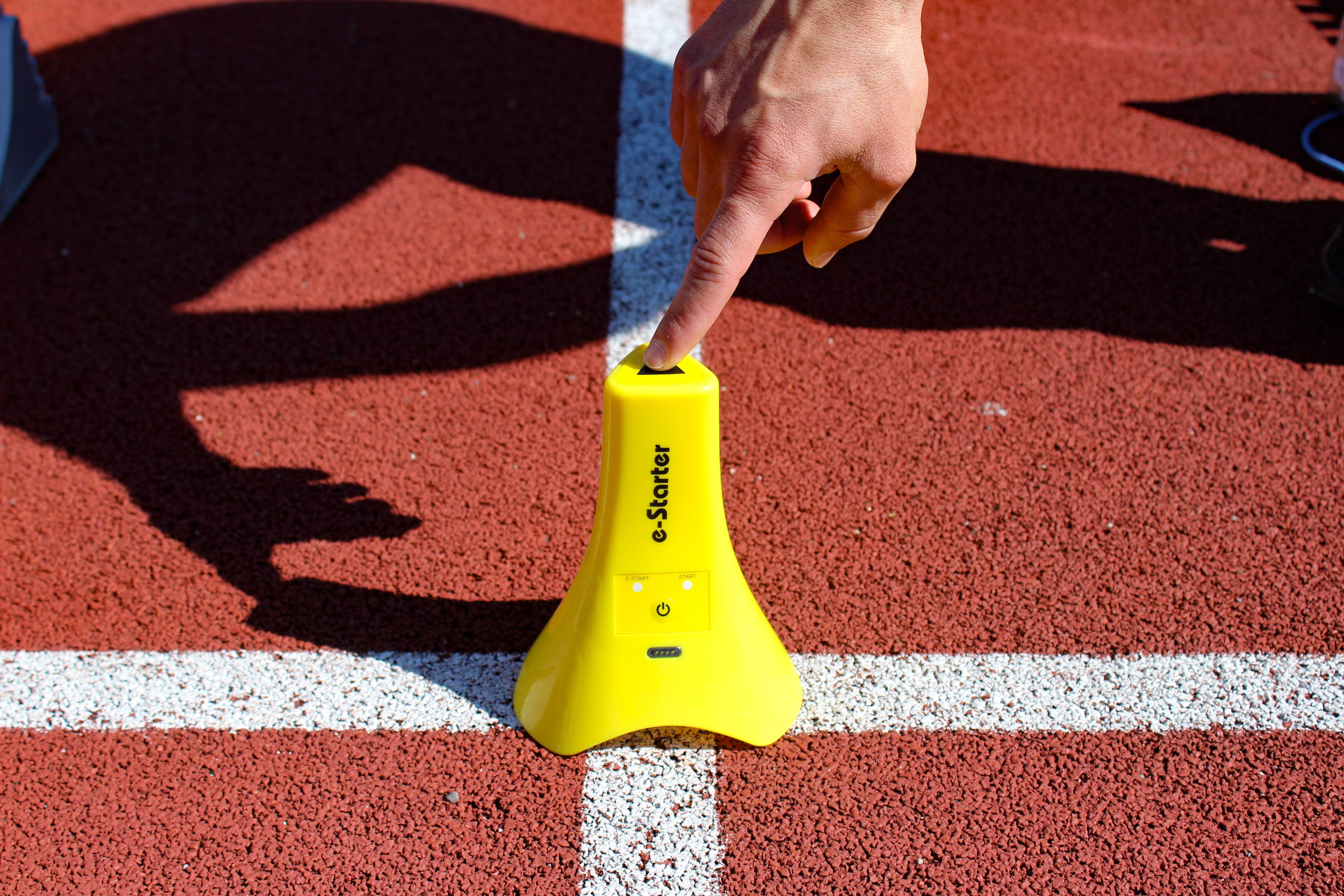 Hand placing a sprint timing transmitter on a track start line for speed testing